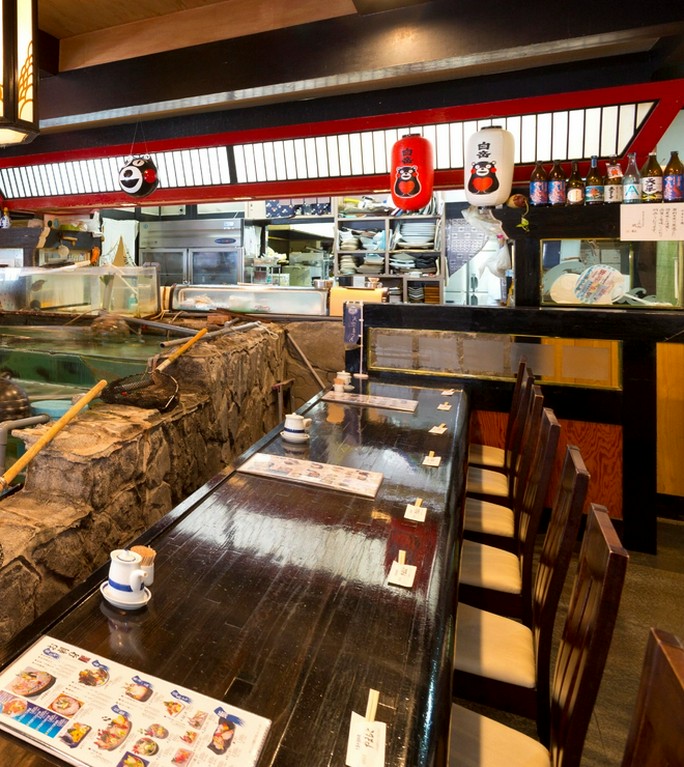 巨大ないけすの前には一人でも楽しめるカウンター席
