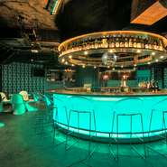 ネオンの光が華やかなアイランドカウンターを中心に、気軽さと上質さを兼ね備えた空間が広がります。