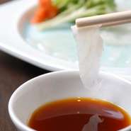 国内産高級トラフグの薄造り。透けるほど薄く引かれた身に弾力のある味わいが。自家製ポン酢を添えて。