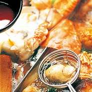 『火鍋』には魚介類や肉、野菜など旬の新鮮具材が用意されています。1人ずつ渡される「マイ網」でしゃぶしゃぶのように具材をくぐらせます。仕切られた鍋に入れられた異なるスープと、具材の組み合わせも楽しんで。