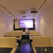 店舗奥のボックス席は全席ソファー席。最大38席の空間には100インチのプロジェクターを装備。普段の映像のほかにパーティーでのご利用の際はお客さまの自由に使っていただけます（追加料金は要りません）。