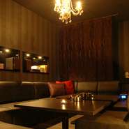 天井にはゴージャスな雰囲気のシャンデリア。黒を基調としたソファに巨大プラズマTVのラグジュアリーな空間