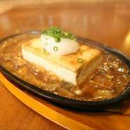 沖縄直送の島豆冨をステーキにしました。熱せられた鉄板に特製きのこあんかけソースがジュ～。