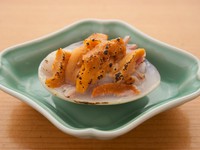 ウニのオレンジ色が目にも鮮やかな一品。千葉県九十九里浜の蛤と北海道のウニを使用。蛤とウニの持つ旨味が織りなす深い味。写真は春の料理（12000円コース）、『蛤のウニ焼』。