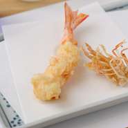 【天ぷら 新宿つな八】の『車海老』は、シンプルでゴージャスさが特徴。活き車海老を注文を受けてからさばき、その場で揚げて仕上げて、お客様に提供します。素材本来の味を思う存分味わえる究極の天ぷらです。	
