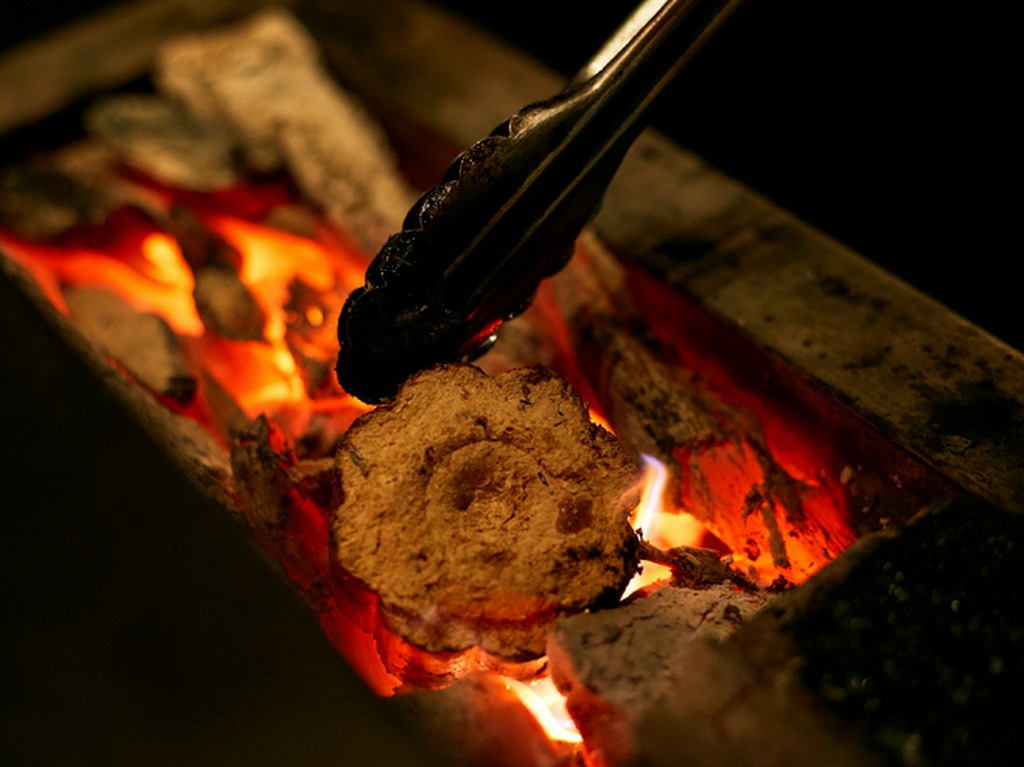 薪の香ばしい香り漂うカウンター前で炭火焼きを堪能