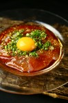 さっぱりしたびんちょう鮪ににんにくを効かせた香味ダレをかけ、香り豊かな金ゴマとねぎをたっぷり使用した一品。濃厚な卵黄と絡めてお召し上がりください。