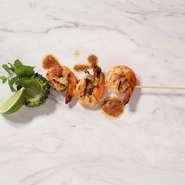 レモングラスやナンプラーでマリネした海老とゴーヤを焼き上げ、凝縮した旨味の海老味噌ソースをかけて仕上げた、トムヤムクンをアレンジした串焼き。フレッシュミント、ライムと合わせて。