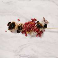 ホタテ、ヤリイカ、マンゴーの串焼きに、スーパーフードのキヌアやビーツ、紅芯大根などで作ったピンク色のタブレ、シンガポールで人気のブラックペッパーソースをかけて仕上げたアレンジシーフード串焼き。