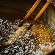 江戸前天ぷら伝統のごま油にいくつかの油を配合し、軽い食べ応えに仕上げます。190～200℃の温度に熱した油の中に次々と食材を入れ、それぞれの最適な秒数をカウントしながら揚げることにこだわっています。