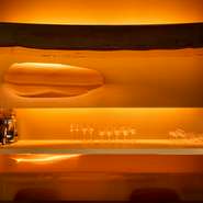 入り口に近いエリアのカウンターやテーブル席には、オレンジの光に包まれた温かな雰囲気が漂います。カウンターの中央に飾られた鏡に映るオレンジの円のオブジェが、まるで太陽のよう。