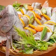 その日市場で選んだオススメの鮮魚を、たっぷりの野菜とともに蒸しあげた一品（写真は鯛）。豪華な尾頭付きなので見た目も迫力満点です。あっさりして食べやすく、大きな魚もペロリと食べられると好評だとか。