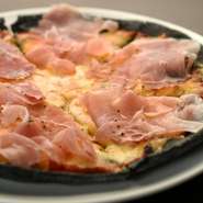 トマトソースをベースとし、玉ねぎ・チーズをのせて焼き上げ、最後に原木からスライスした生ハムをトッピング。インパクトのある黒い生地はイカスミを練り込み、口の中でふんわりと香りが広がります。
