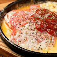 スライストマトの上に、ミックスチーズをたっぷり乗せた『たっぷりチーズとトマトの鉄板焼き』。チーズはパルメザンチーズなど3種類をミックスし、トマトの酸味とチーズの濃厚なコクが楽しめる一品です。