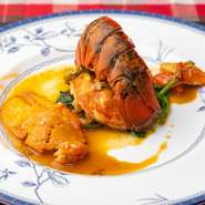 生きたオマール海老の蒸し焼きを、殻と魚介にブランデーを加えてパンチを出したソースで。プリプリの食感はやみつきになる美味しさ。コライユ（オメールエビのミソ）も添えられています。