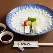 噛んだ時に程よい歯応えとポン酢の香り、旨みを感じられるように、厚めに切られたフグの刺身です。一番外側の鮫皮、プルッとした口当たりのとうとうみ、身も付いて歯応えがある身皮と3種の皮の湯引きも味わえます。