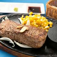超厚切りの肉が豪快に味わえる、牛モモ肉の『パワフルステーキ』。自家製のガーリックオニオンソースが鉄板の上で弾け、食欲をそそる香りが広がります。味、ボリュームともに大満足な一皿です。