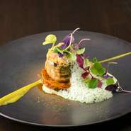 シェフが得意とする南仏の郷土料理をガストロノミーに昇華。ズッキーニに豚挽肉、オリーブ、香味野菜などを詰めて揚げ、バジル＆オリーブオイルベースの泡をまとわせ、重層的な味わいが響く一皿に。温前菜の一例。