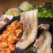 厚みが約1cmほどある豚バラ肉を、こんがり焼いて、キムチやネギと一緒にサンチュに包んでいただきます。大阪鶴橋から仕入れる本場の味噌ダレが味の決めて！