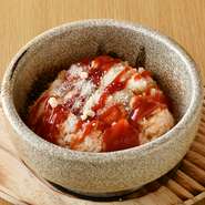 特製のチキンライスの上に生卵やトマトソース、パルメザンチーズなどをトッピング。半生で味わう卵かけスタイルや、石焼の縁で焼き上げおこげをつくってから食べるなど、幅広いチキンライスの味わい方を楽しめます。