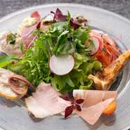 入荷した素材で、その日一番おいしいものが並ぶ『本日の前菜いろいろ』。『鮮魚のカルパッチョ』や『匠味豚の自家製ハム』、『シラスとサバのキッシュ』などと、地元産野菜が味わえます。