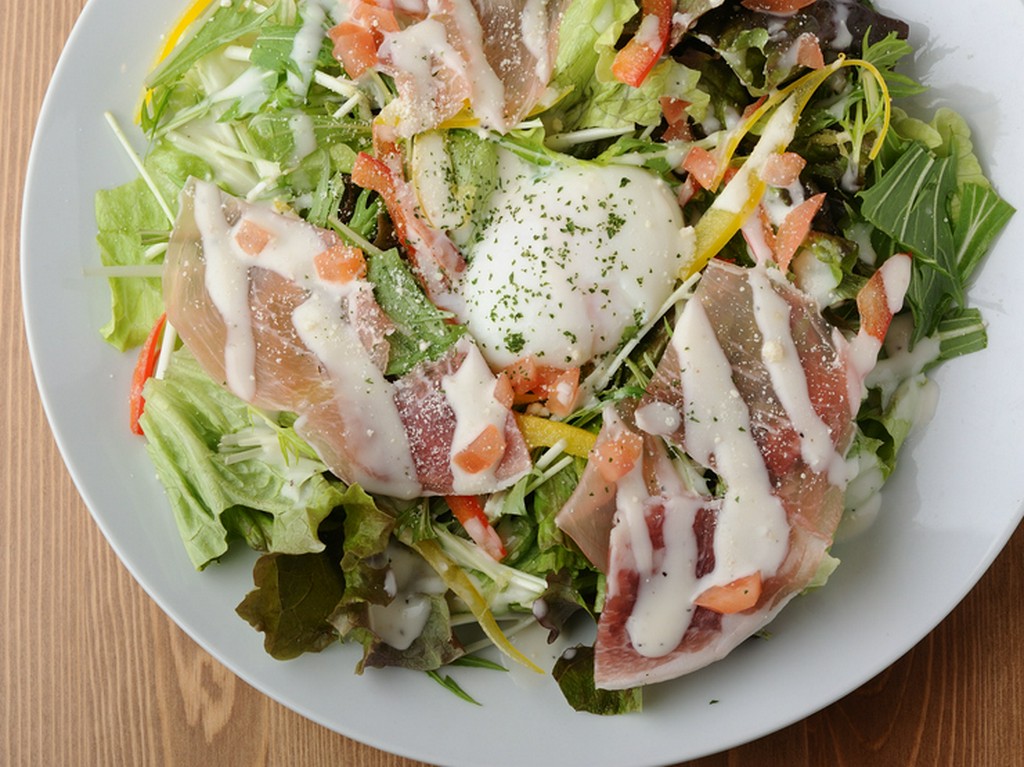 自家製ドレッシングを使った『生ハムと温玉のシーザーサラダ』は女性に人気