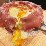 当店名物とろとろのチーズ4種が溢れ出すシカゴピザ。写真は生ハム温玉シカゴピザ。他にも自家製ボロネーゼを乗せたクワトロシカゴピザ（税込1859円）や、トマトソースマルゲシカゴピザ（税込1749円）も