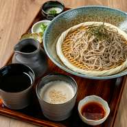 上質な鰹節を使い、毎日丁寧に引くだしの旨みたっぷりな「つゆ」と、胡麻を合わせてつくる「胡麻つゆ」。二つの味を贅沢に堪能できる人気の味わい。（そば、胡麻つゆ、そばつゆ、薬味、とろろ、漬物、デザート付）