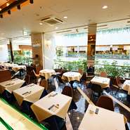 大きな吹き抜けが見える店内は、開放感にあふれながらも落ち着いた雰囲気が漂います。白いテーブルクロスが整然と並ぶ上品な空間は、特別な日や大切な人との食事にふさわしい洗練された佇まいです。