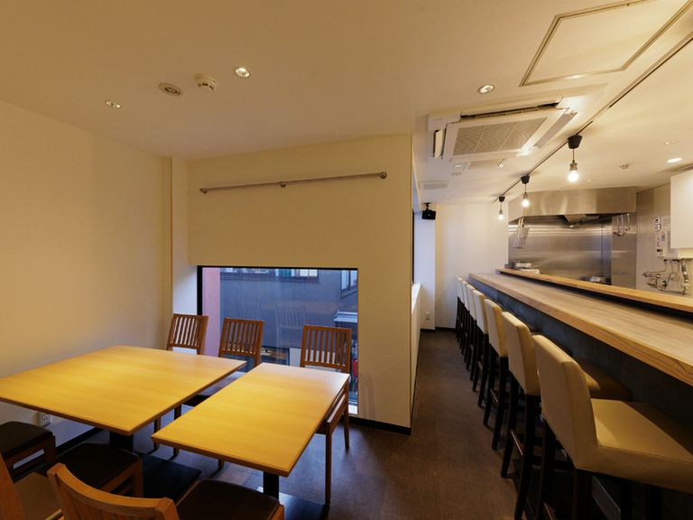 清潔感のある白一色の部屋。木目を基調とした席で食事を楽しむ