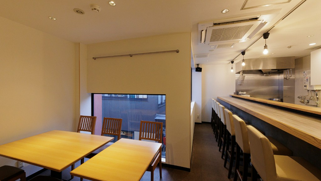 清潔感のある白一色の部屋。木目を基調とした席で食事を楽しむ