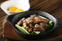 豚のレバーとハツを秘伝の生姜醤油タレに漬けこんだレバーを、卓上直火焼きで鉄鍋仕上げのレバニラ。すき焼き風に卵黄に潜らせてお召し上がる映え料理が人気