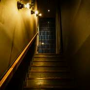 【No Code】と控えめに書かれた店名を目印に扉を開けると、2階へと続く階段が現れます。非日常の世界へと誘うような幻想的な照明やネイビーのタイルが印象的な空間の先に、わずか8席のカウンター席が。