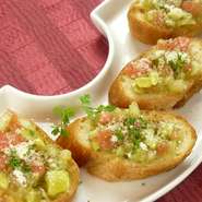 こんがり焼いたガーリックトーストに、アボカドとトマトなどをのせたブルスケッタ。イタリア料理の軽食の一つ。おつまみや前菜とししてどうぞ。