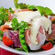 サラダの上にプロシュート（生ハム）をトッピングし、チーズソースをかけました。