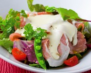 サラダの上にプロシュート（生ハム）をトッピングし、チーズソースをかけました。