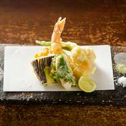 旬の魚介や野菜をサクサクの天ぷらに。約6～7種を盛り込んだ目にも楽しい一皿です。春野菜、夏のハモ、秋はきのこと、四季折々の食材で季節を存分に堪能できます。