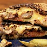 話題のニューヨーク生まれのホットサンド。バターでこんがり焼いたパンに、たっぷりレッドチェダー、モッツアレラ、ミックスチーズを挟んで半分カット。こぼれ落ちる断面チーズはチーズ好きにはたまりません。