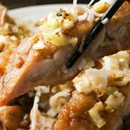 鶏もも肉を切らずに自家製タレに漬け、そのまま揚げた豪快な一品！山盛りのネギと一緒にお召し上がりください。