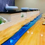 カウンターテーブルには海を表したブルーが入り、キッチンとの境には沖縄珊瑚からできた仙人岩のような琉球石灰岩が飾られています。孫悟空が乗る筋斗雲みたいな串揚げ皿など、宝船に乗った気分になれる店内です。