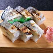 宮崎のブランド魚「ひむか本サバ」を半身丸ごと使った押し寿司。脂がのって旨みが詰まった肉厚のひむか本サバをシャリの中にも入れ、2段に重ねています。ボリュームがあるので2～3人でシェアして。