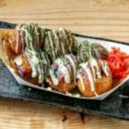 揚げたこ焼きは、サクサクの食感が特徴で、中にはふんわりとしたお好み焼きの具が詰まっています。この美味しいおやつは、特製のソースとクリーミーなマヨネーズが絶妙なバランスで絡み合います。