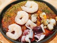 広島風お好み焼き「海鮮焼」は、もちもちの生地に麺、新鮮な海老、イカ、ホタテをたっぷりとトッピングした美味しい一品です。特製のソースとマヨネーズが海の風味と絶妙に調和し、豊かな旨味が楽しめます。