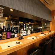 清潔感あふれるカウンターの一角には、日本酒や焼酎のボトルがずらりと並びます。季節のお酒や隠れた銘酒がそろい、新しい味に出合えるのも楽しみの一つ。好みのグラスを傾けながら、贅沢な時間を過ごせます。