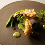 カリカリのべニエ生地を纏ったサザエは、旨みが凝縮された食感が楽しい。エスカルゴバターでソテーした甘み溢れるズッキーニや、鮮やかな色合いのアスパラソバージュを添えることで旬を表現しています。