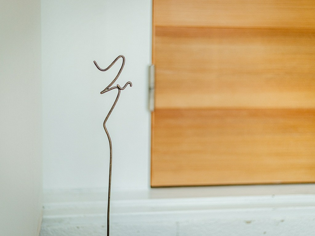 玄関先、床からすっと伸びる草書体の【いづく】の文字