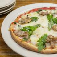 大将の弟が北谷で開店しているパン屋さんで作られた、本格的な生地を使用。もちもちの歯応えが絶妙です。ここにピザソースとアグー豚の豚バラ、ミックスチーズをかけて焼き上げ、最後にフーチバーを散らしました。