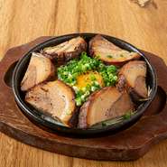 鉄板に焼いたネギ、炙ったチャーシュー、目玉焼きを乗せました。黄身と絡めて召し上がれ！

