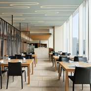 大きな窓が解放感を演出するテーブル席。昼は光が差し込み、夕刻には夕日が望め、夜は夜景を楽しめます