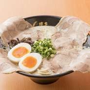 スープを覆う4枚の大振りの肩ロースチャーシューは濃厚なスープとの相性抜群。半熟玉子も付いた贅沢な一杯